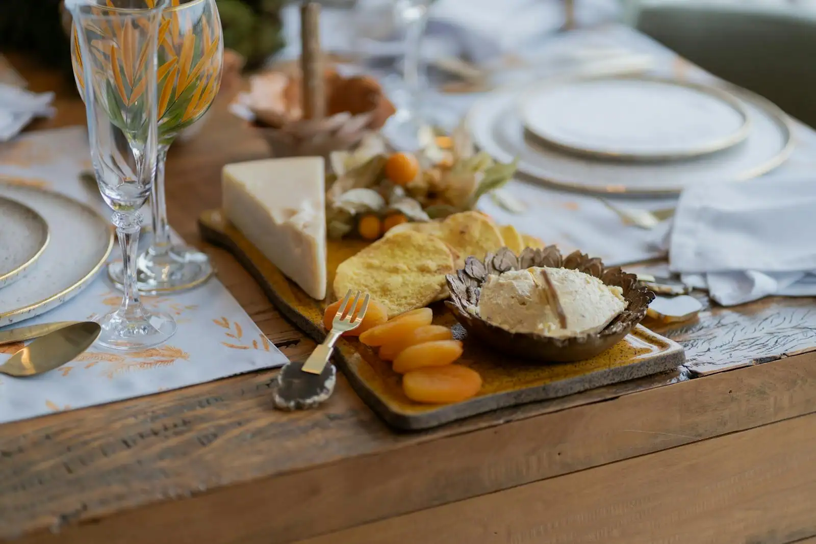 Table d'apéro dînatoire dressée à la maison, planches de charcuterie, fromages et tartinables, chandeliers allumés et lumière chaude