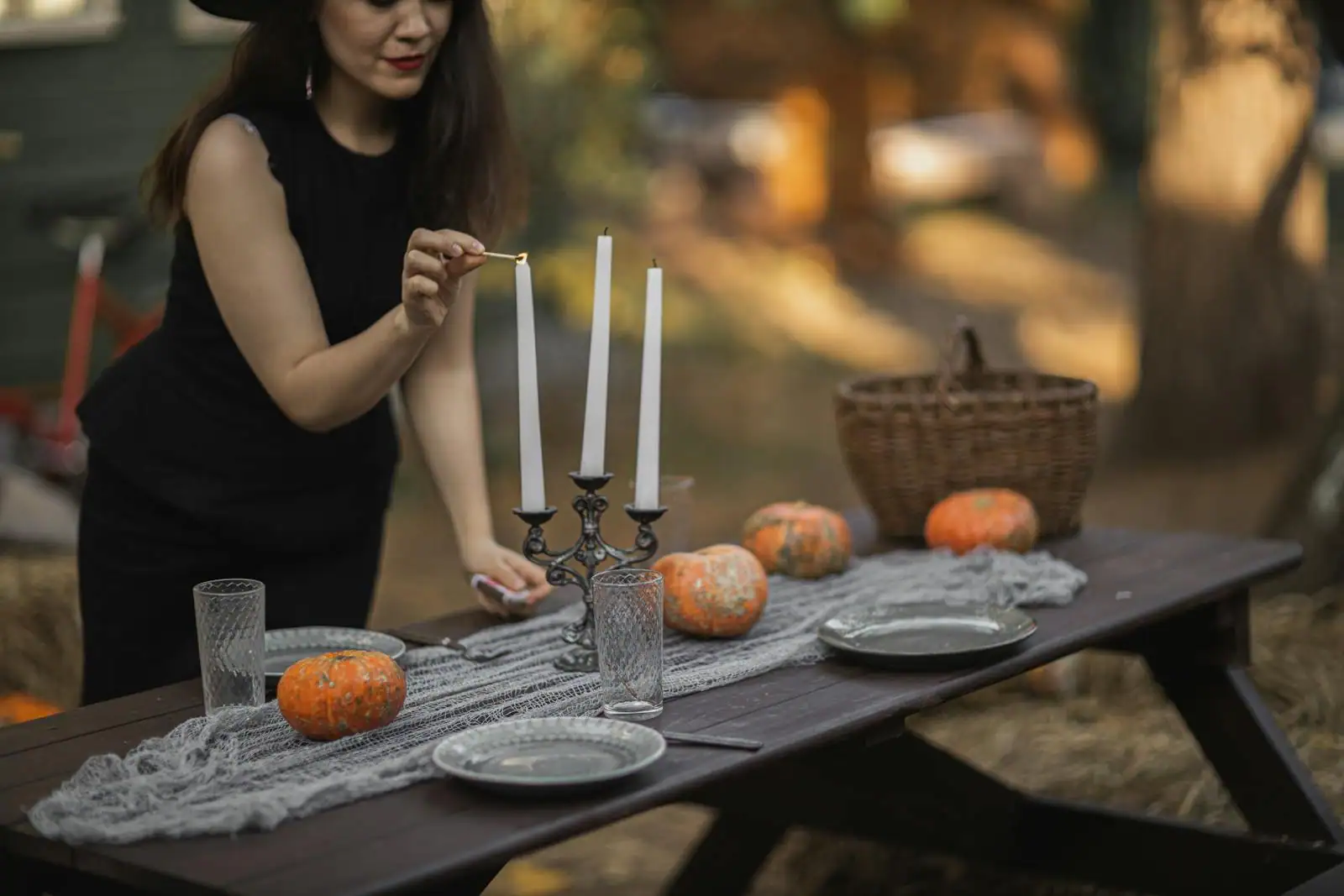 Table d'automne dressée pour Halloween avec soupe de potimarron servie en coque, bougies hautes, feuilles d'érable et toasts de pain noir en arrière-plan