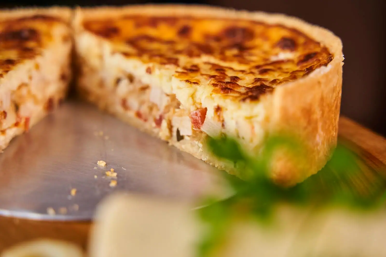 Quiche lorraine dorée tranchée sur un plat en céramique avec une part découpée