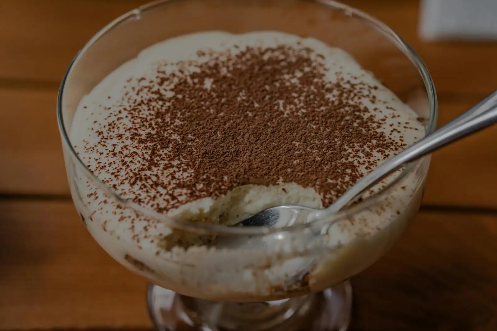 Tiramisu traditionnel saupoudré de cacao avec une part découpée laissant voir les couches
