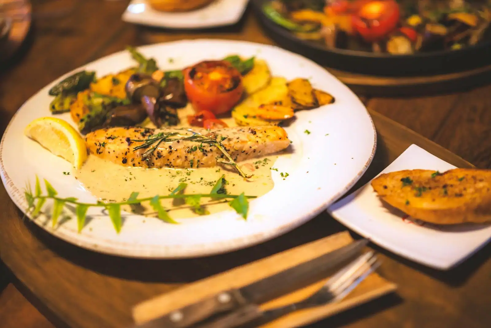 Assiette de dîner léger avec poisson grillé et légumes verts cuits, dressage sobre sur table claire