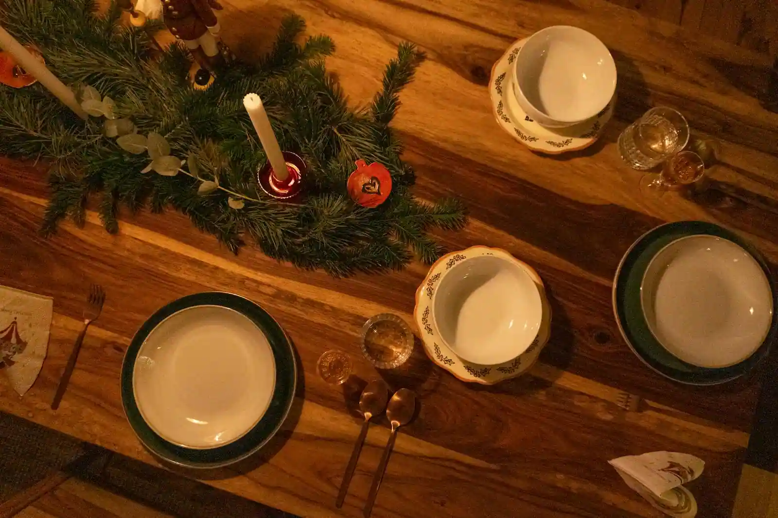 Table de Noël dressée à la bougie : assiettes de présentation dorées, verres à pied et linge de lin écru.