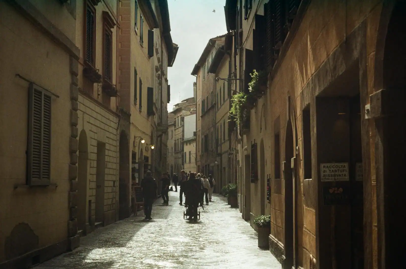 Ruelle pavée d'une ville italienne avec étals de marché et trattoria locale