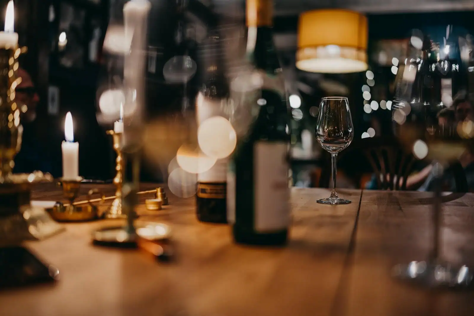 Verre de vin jaune doré posé à côté d'un clavelin de 62 cl, table en bois sombre