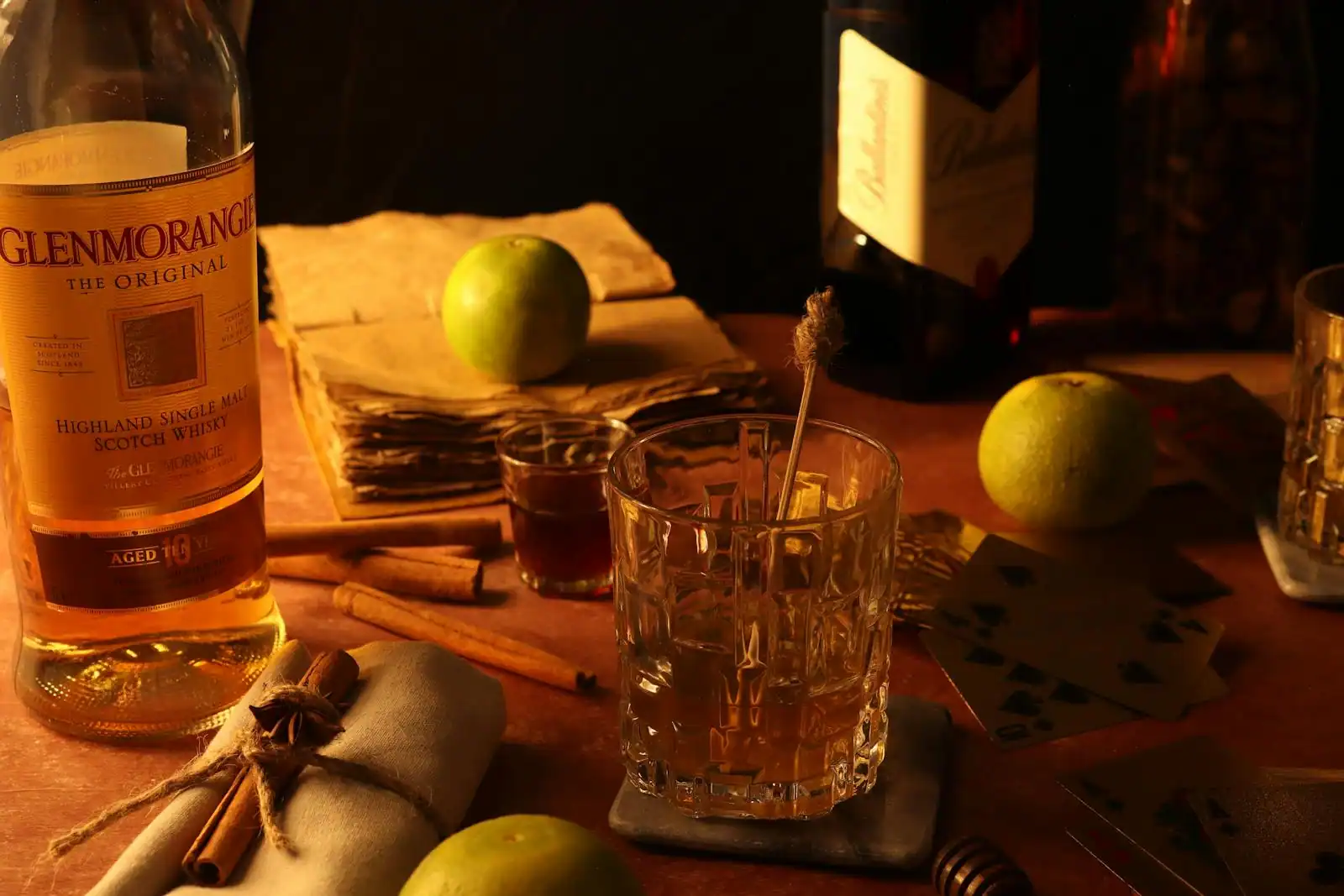 Verre tulipe de whisky ambré sur une table en bois sombre, bouteille en arrière-plan