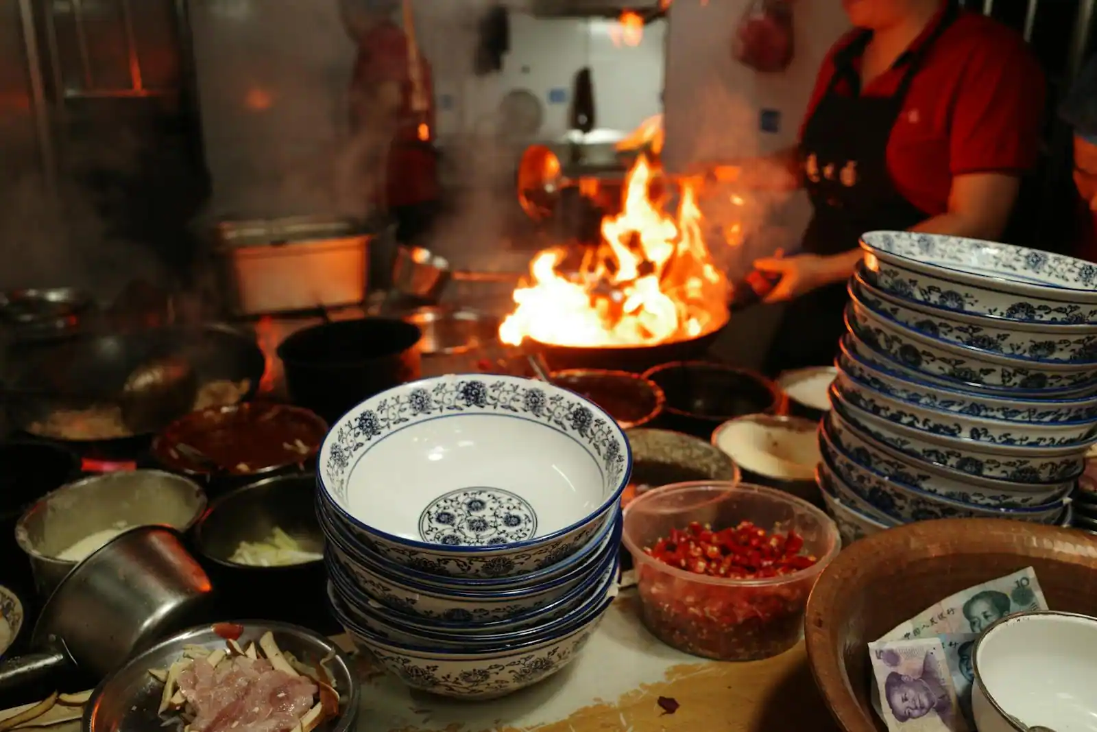 Cuisinier préparant un wok minute avec légumes et viande sur un feu vif