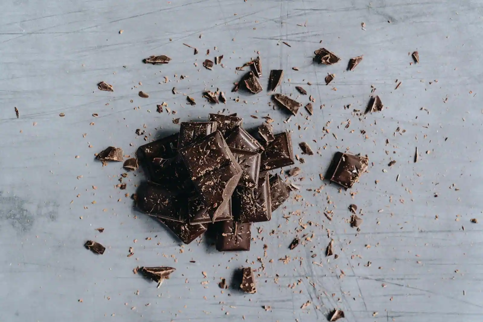 Carrés de chocolat noir cassés et fèves de cacao sur un plan en bois, gros plan gourmand