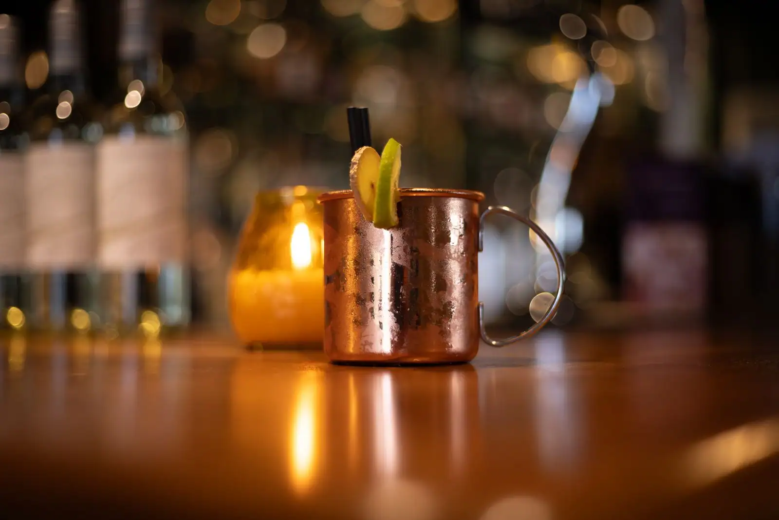 Cocktail Moscow Mule dans un mug en cuivre martelé, garni de citron vert, sur un comptoir de bar