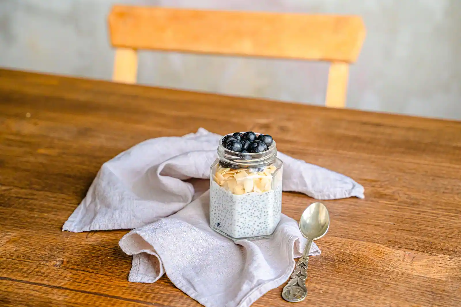 Un bocal de pudding de graines de chia garni de myrtilles et de fruits, posé sur un torchon.