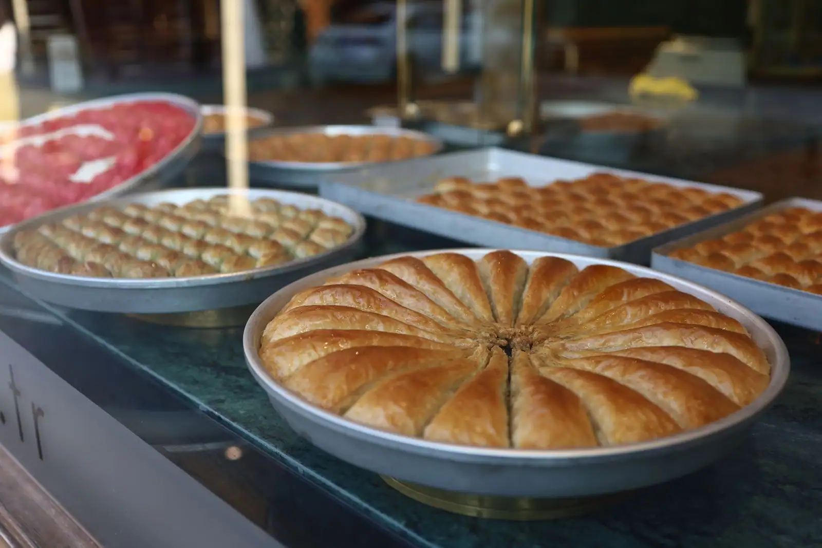 Plateaux de baklava turc doré découpé en parts, en vitrine d'une pâtisserie.