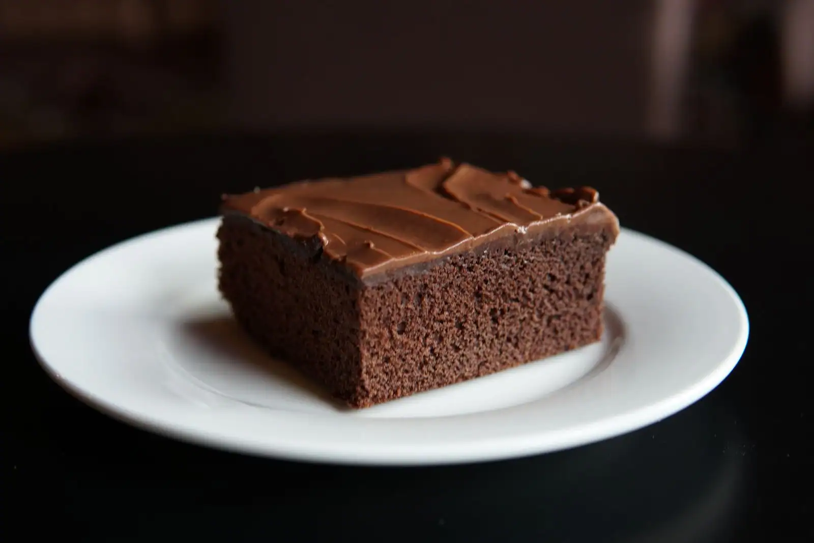 Une part de gâteau au chocolat fondant et moelleux, posée sur une assiette claire, prête à être dégustée.