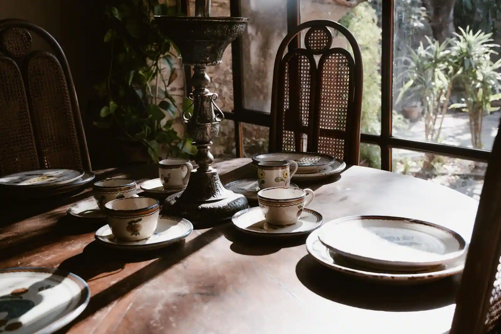 Assiettes anciennes en porcelaine à motifs, empilées sur une table en bois, évoquant la vaisselle vintage