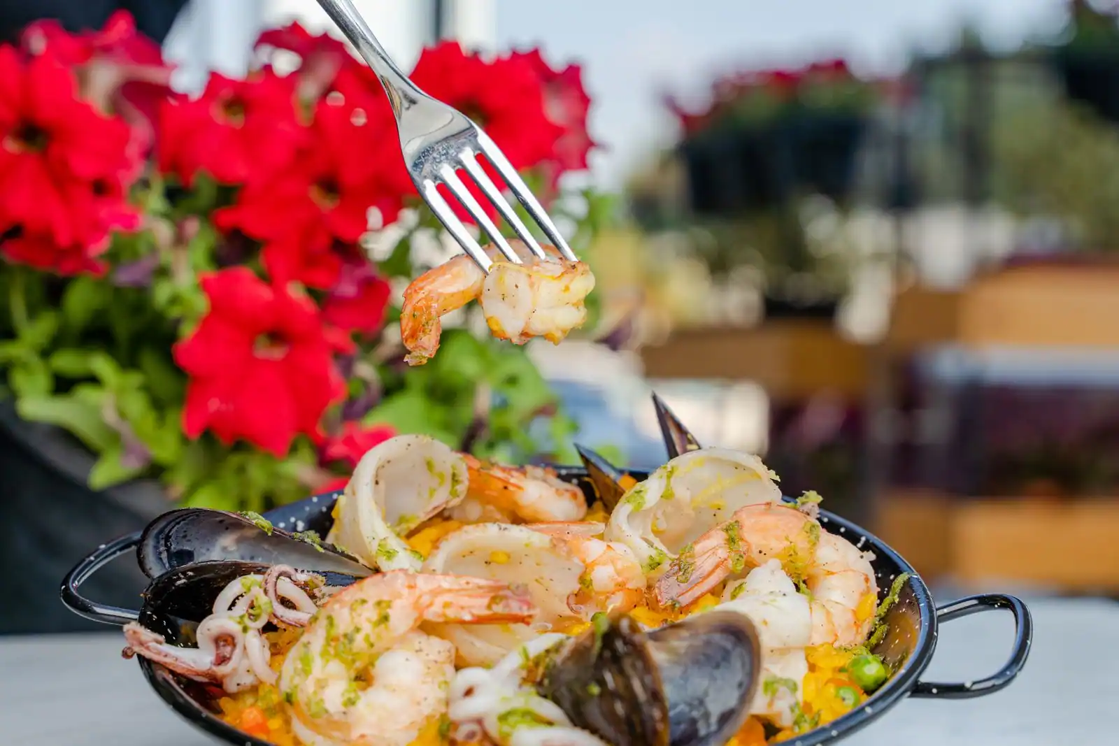 Paella aux fruits de mer dans une poêle noire, garnie de gambas, moules et calamars sur riz au safran