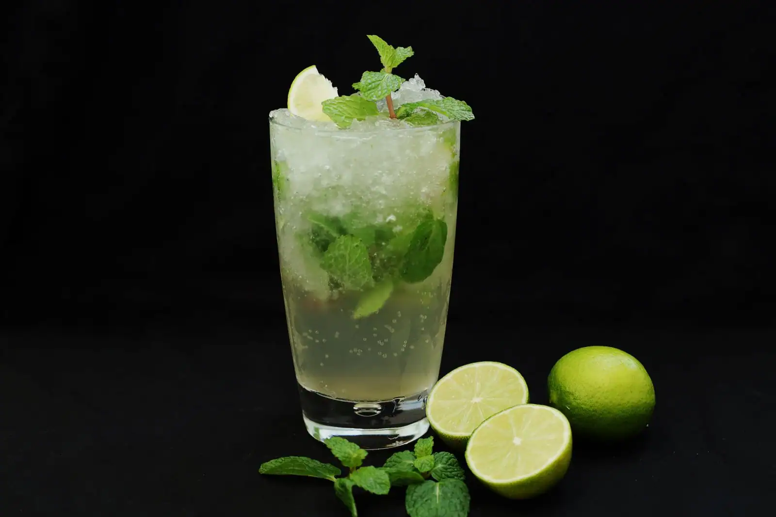 Cocktail au rhum type mojito servi avec citron vert, menthe fraîche et glace dans un verre