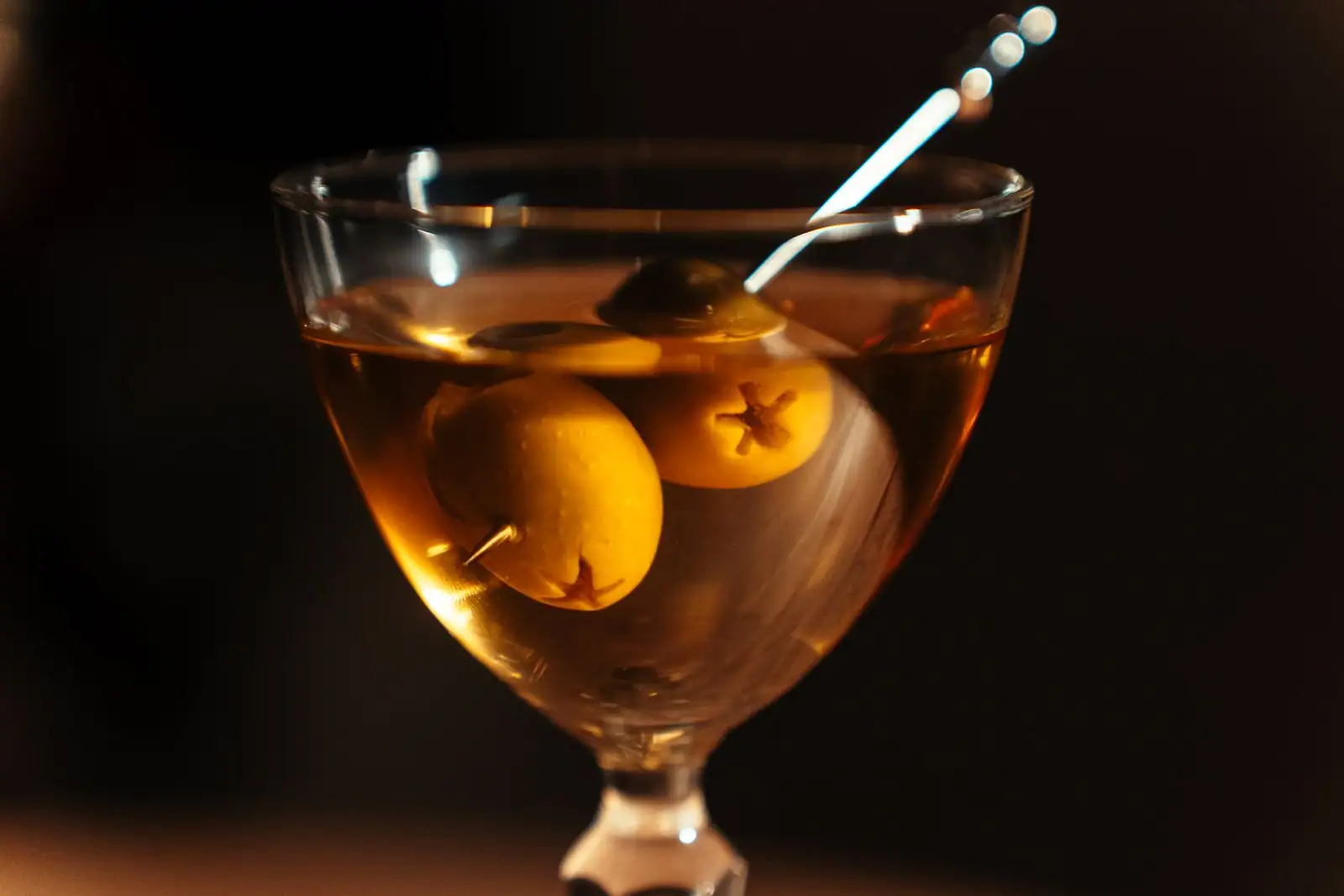 Dry martini limpide dans un verre à cocktail avec une olive verte sur un comptoir