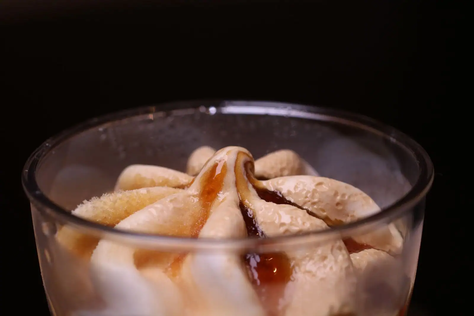 Sundae glacé nappé de caramel servi en gobelet, cuillère posée à côté