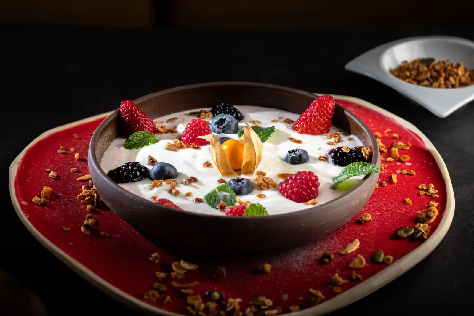 Bol de fromage blanc garni de fruits rouges frais, physalis, menthe et granola, dessert léger