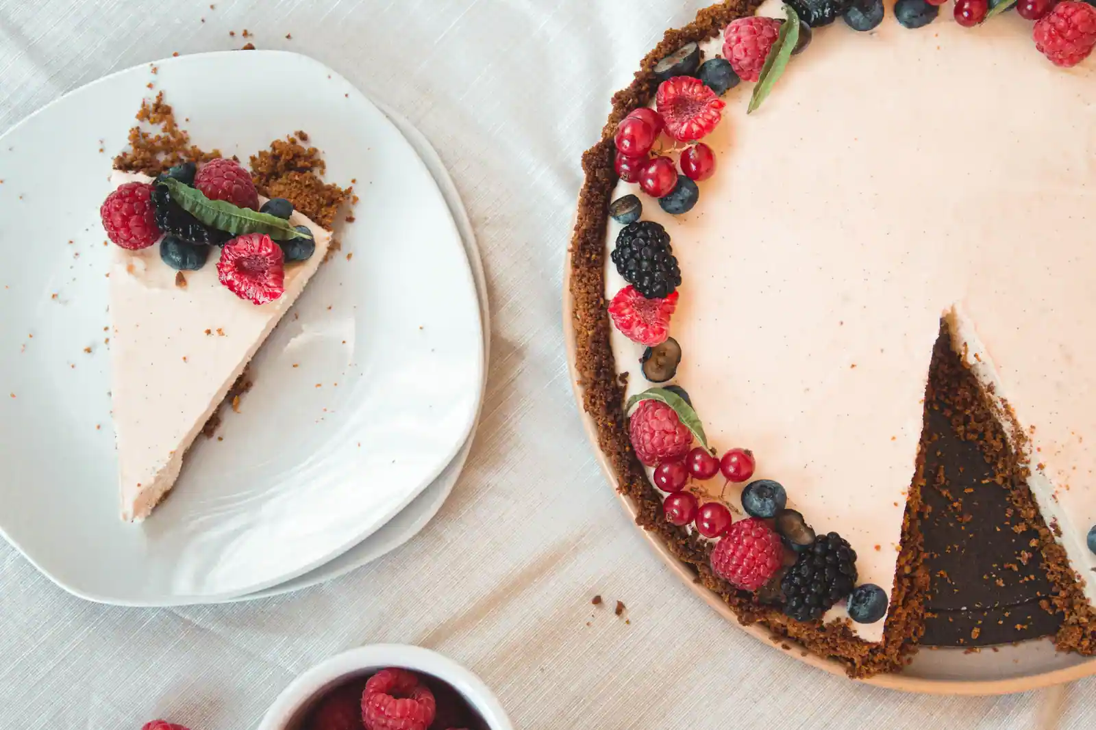 Cheesecake sans cuisson à base de biscuits, nappé de fruits rouges frais, avec une part servie