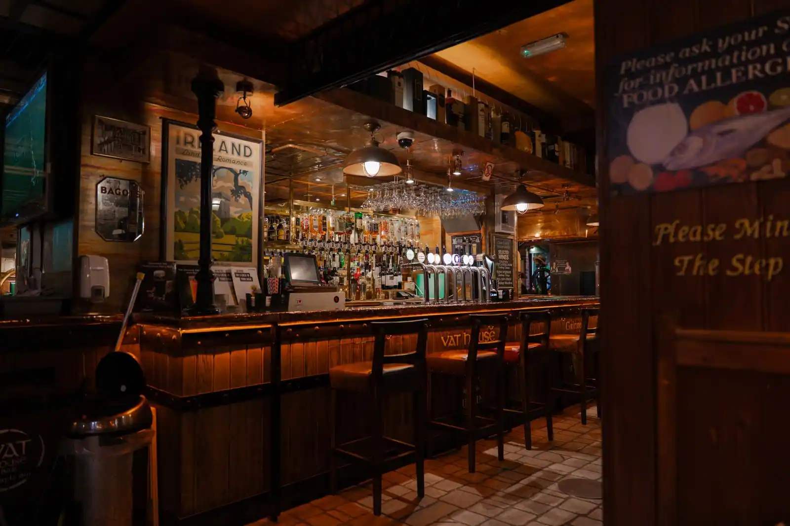 Intérieur chaleureux d'un pub avec comptoir en bois et pintes de bière pression