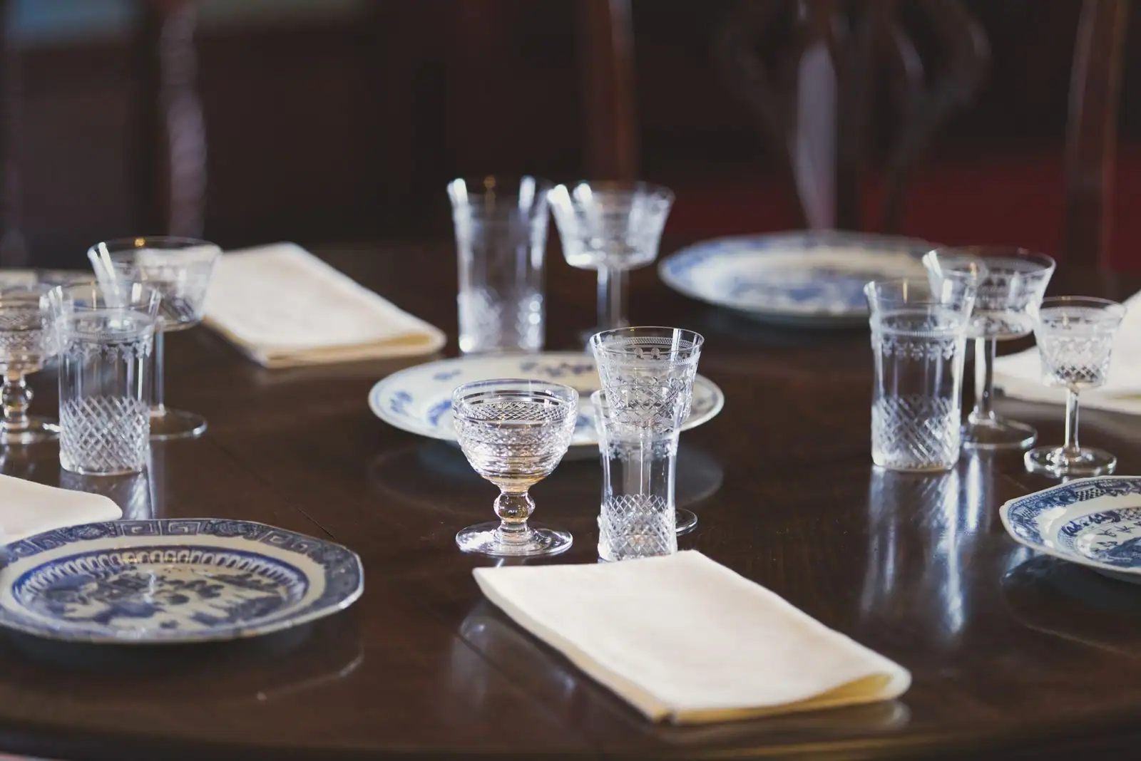 Table dressée avec assiettes en porcelaine à décor bleu, verres en cristal taillé et serviettes en tissu