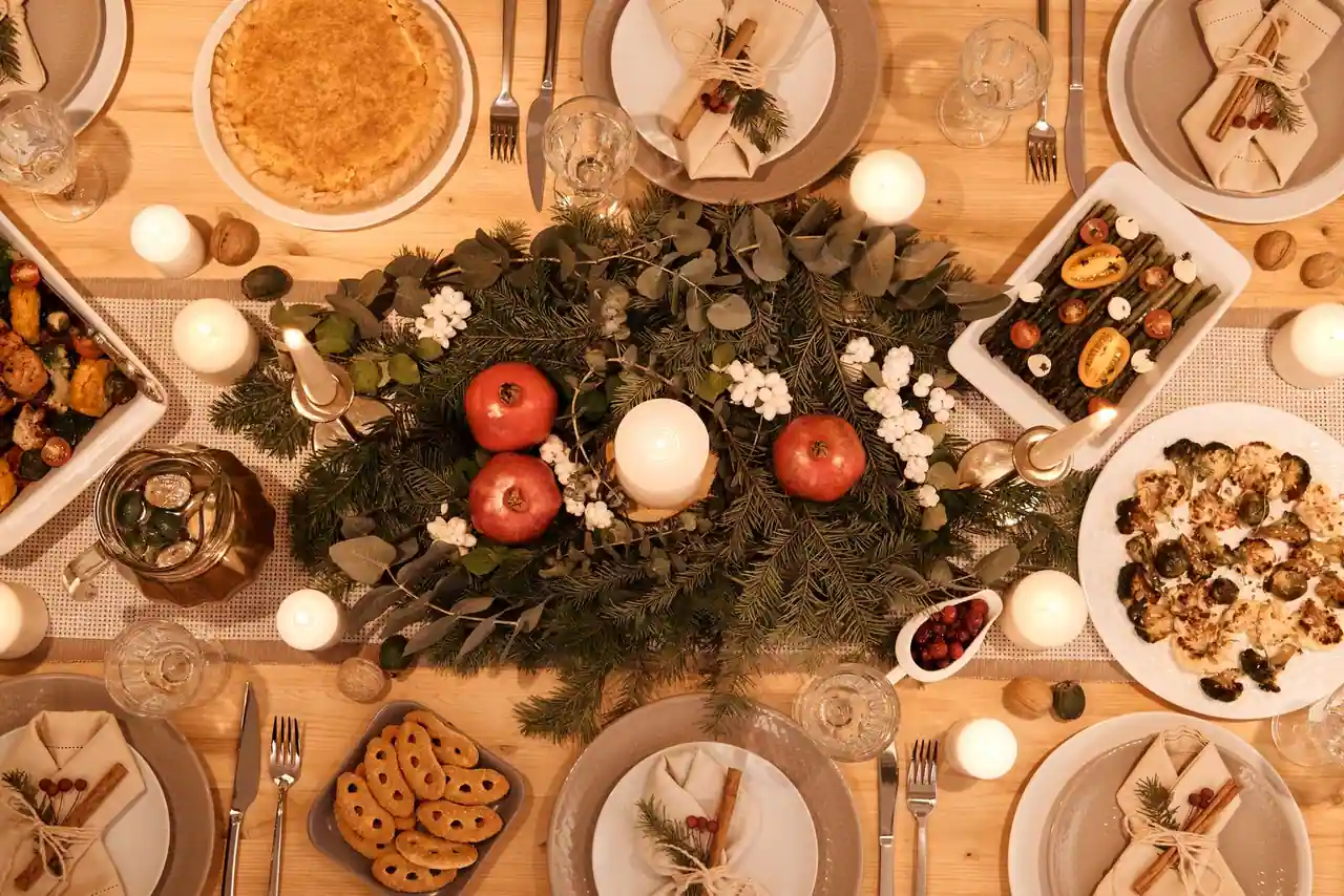 Table de fête de Noël vue de dessus, dressée avec des plats de légumes rôtis et des bougies allumées