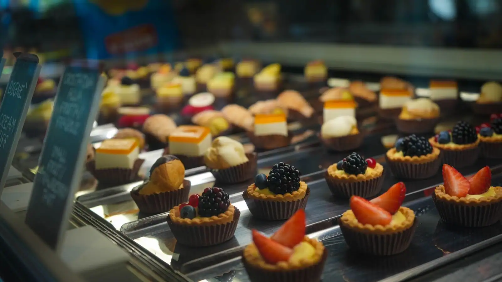 Vitrine de pâtisseries fines : tartelettes aux fruits rouges et petits choux à la crème