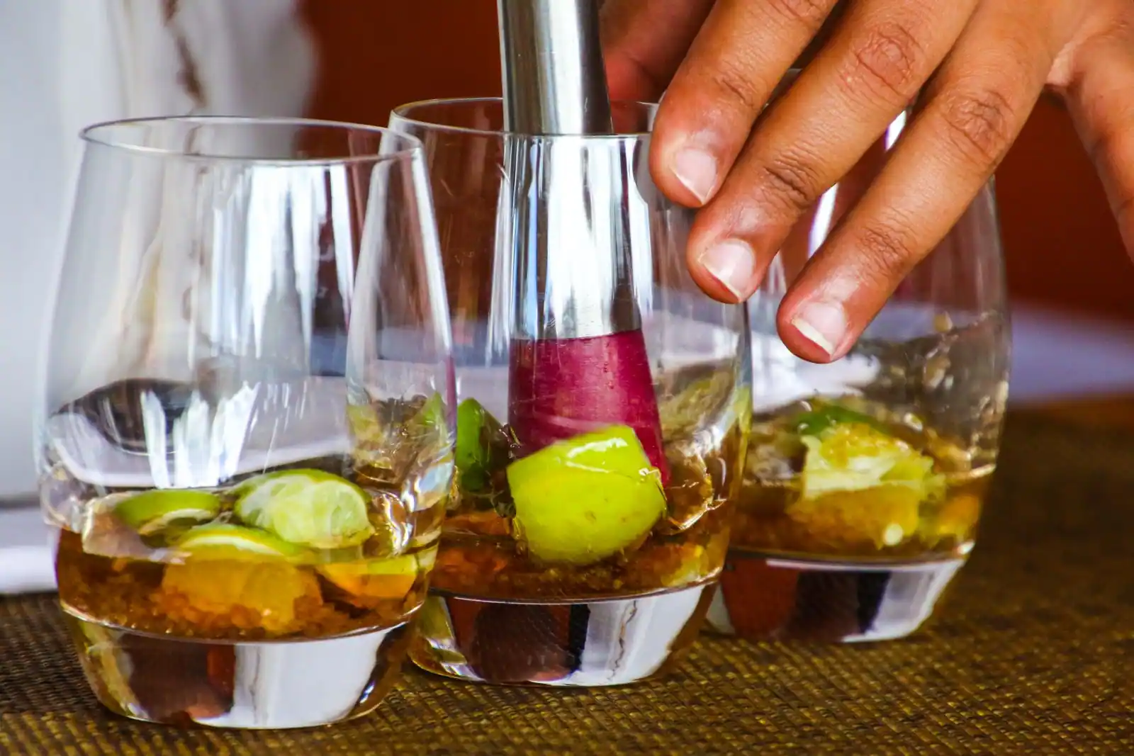 Préparation d'une caipirinha : citron vert et sucre pilés au pilon dans des verres bas