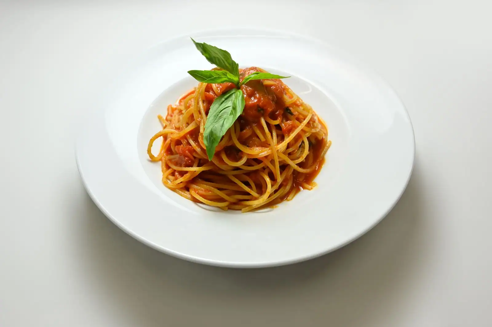 Assiette de spaghettis italiens enrobés de sauce, avec fourchette et parmesan