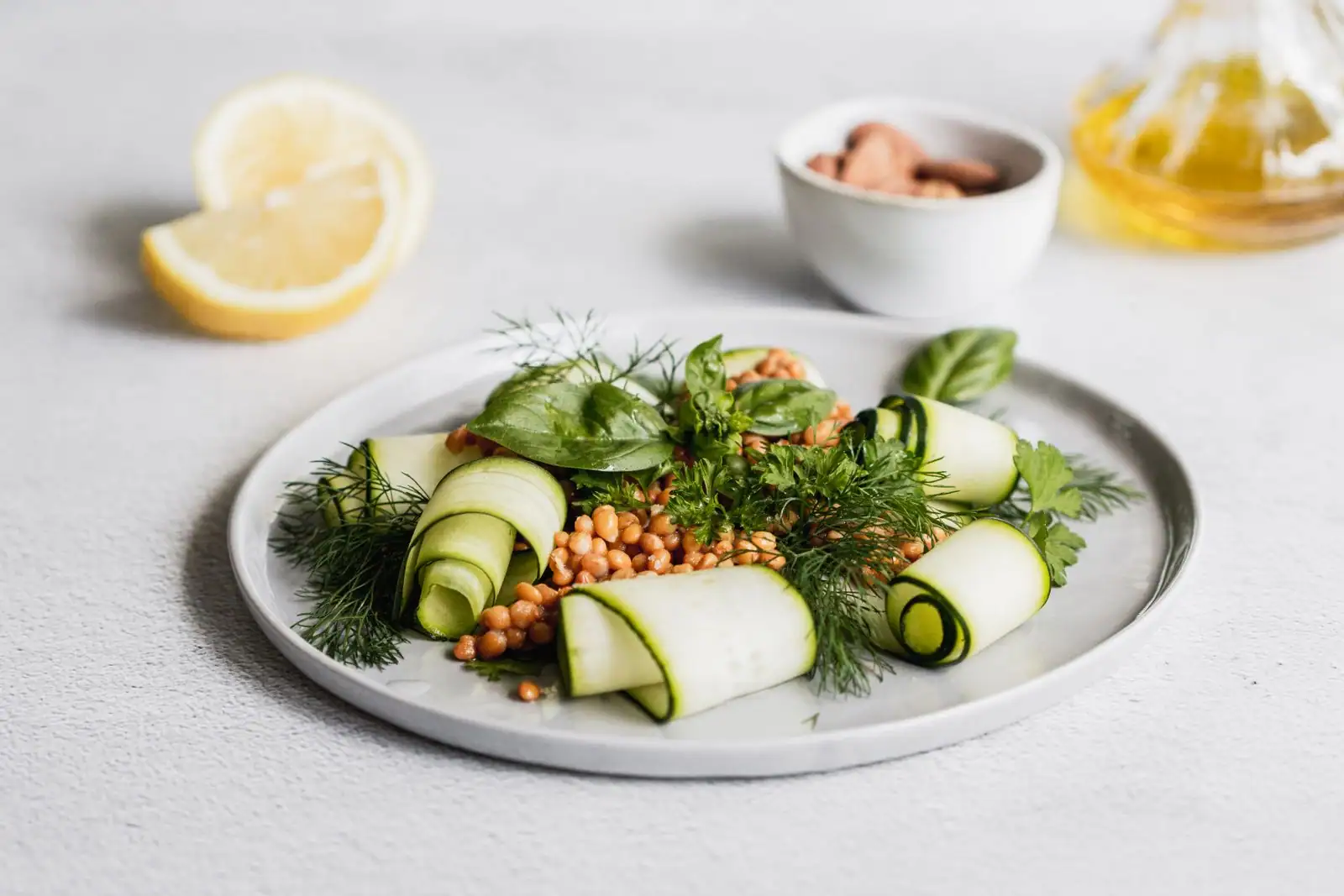 Assiette végétarienne avec rubans de courgette crue, céréales, herbes fraîches, citron et huile d'olive