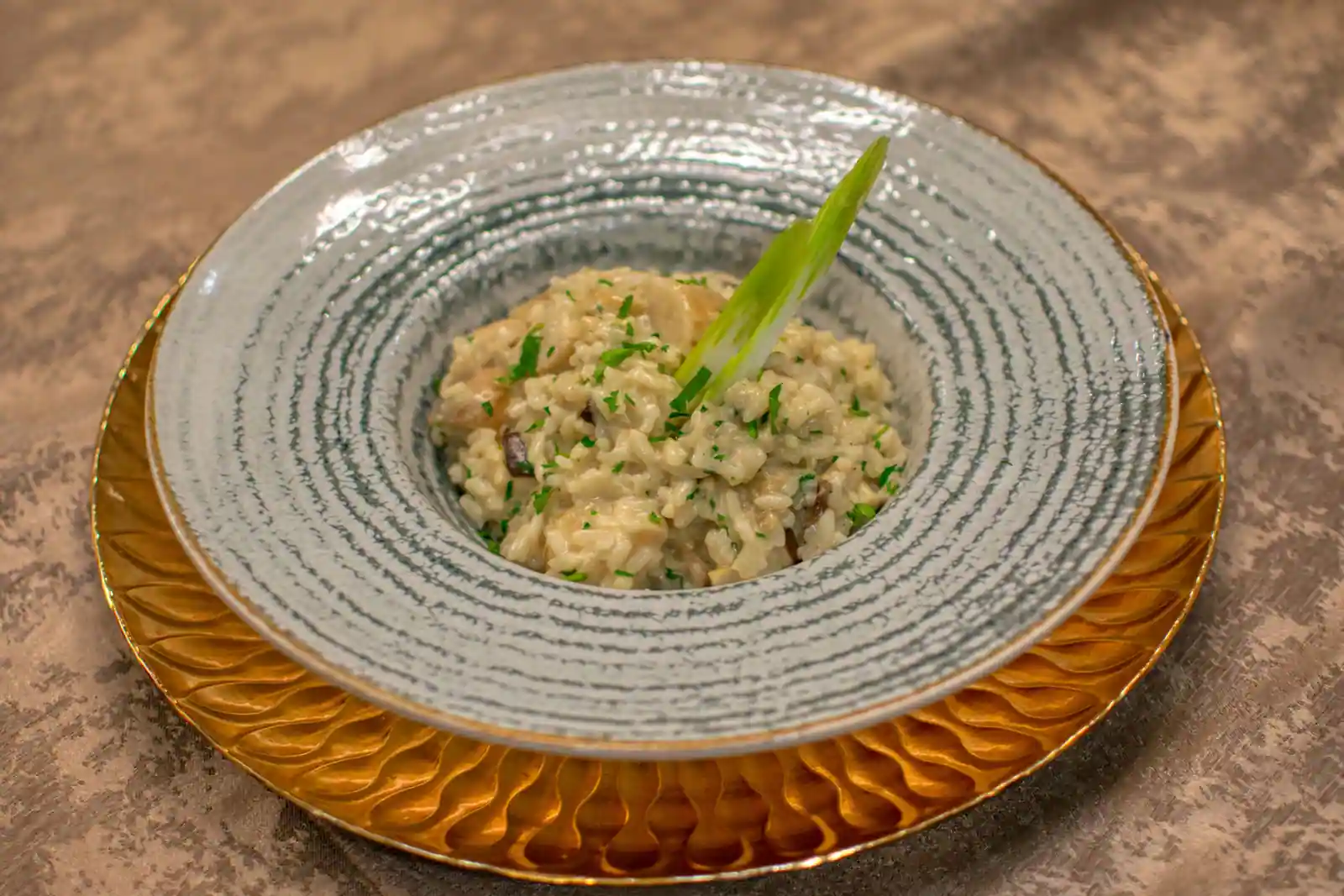 Risotto crémeux aux champignons servi dans une assiette creuse, garni de persil