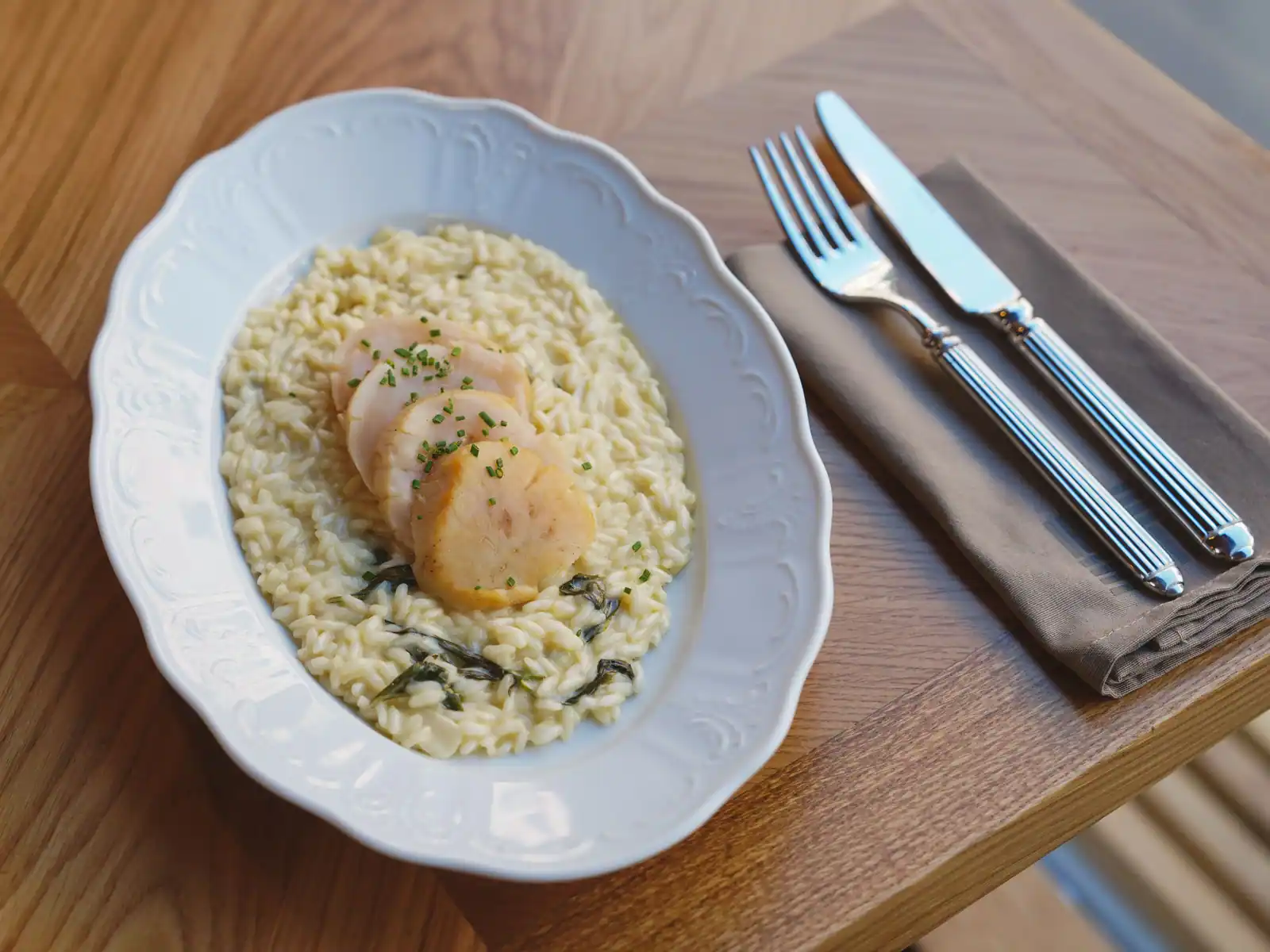 Risotto crémeux et nacré, à la texture onctueuse, dressé dans une assiette blanche
