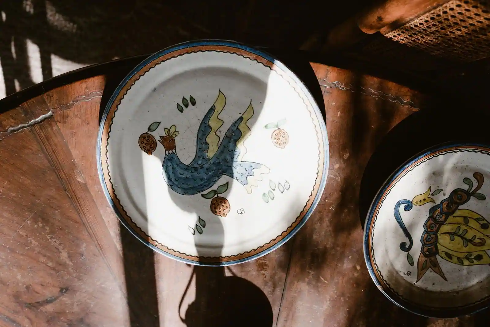 Vaisselle en céramique peinte à la main, deux assiettes à motifs d'oiseau posées sur une table en bois