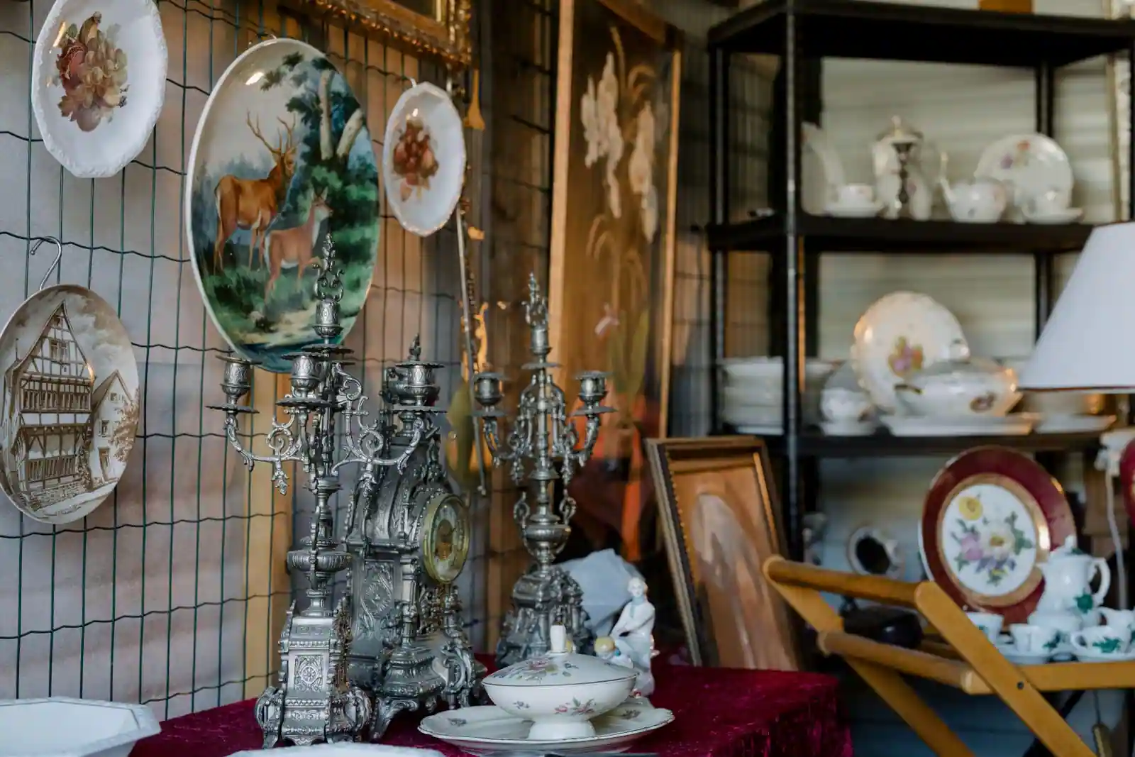 Stand de brocante présentant de la vaisselle ancienne en faïence : assiettes décoratives, légumier et service