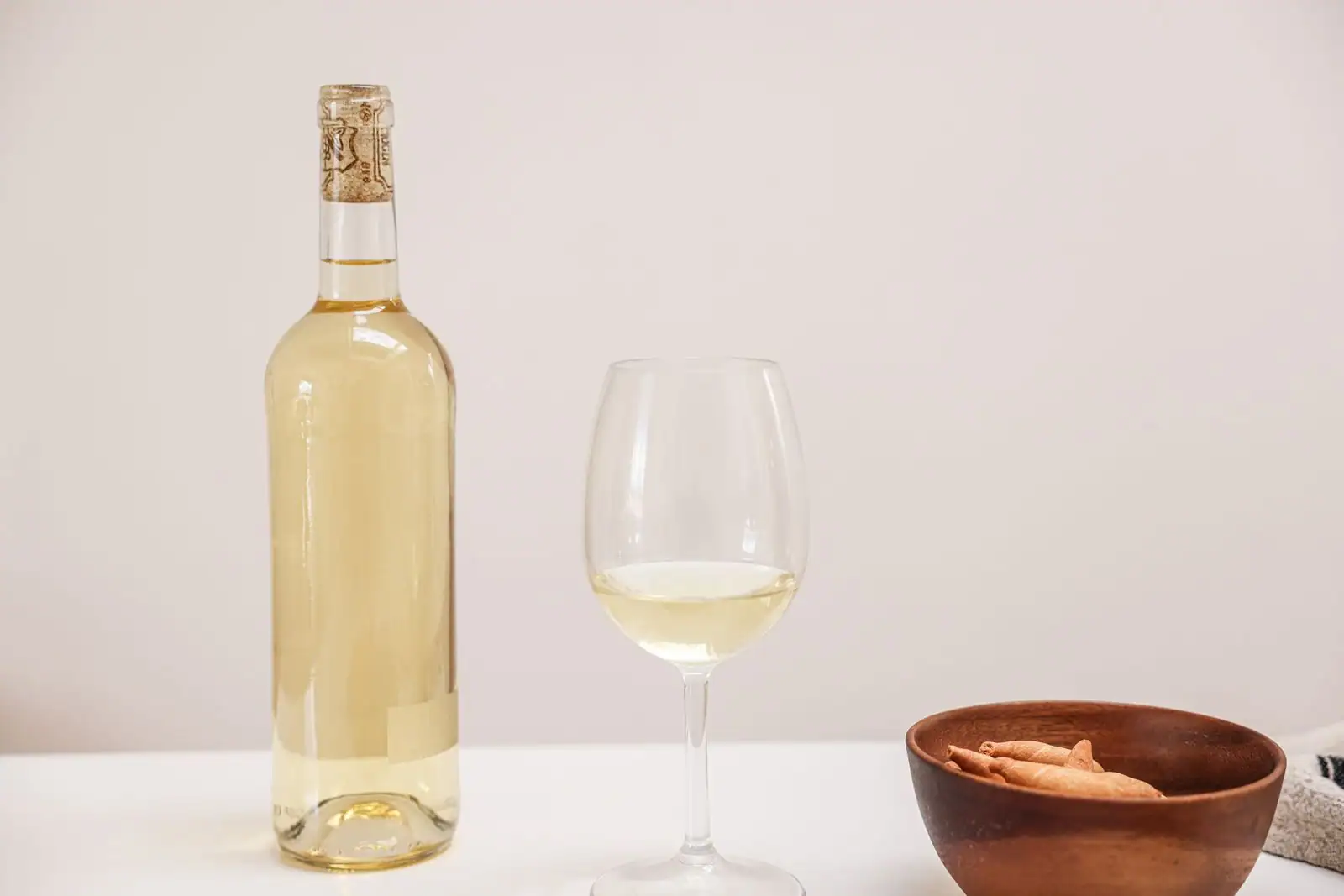 Verre de vin blanc et bouteille élancée posés sur une table dressée pour la dégustation