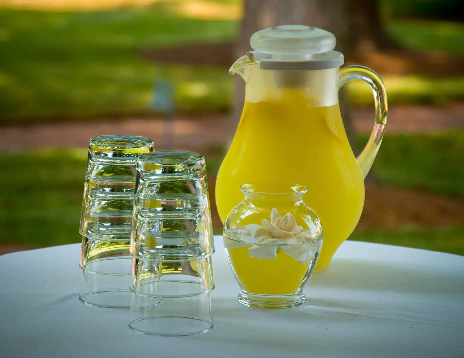 Pichet en verre rempli de limonade, fermé par son couvercle, et verres vides retournés sur une table