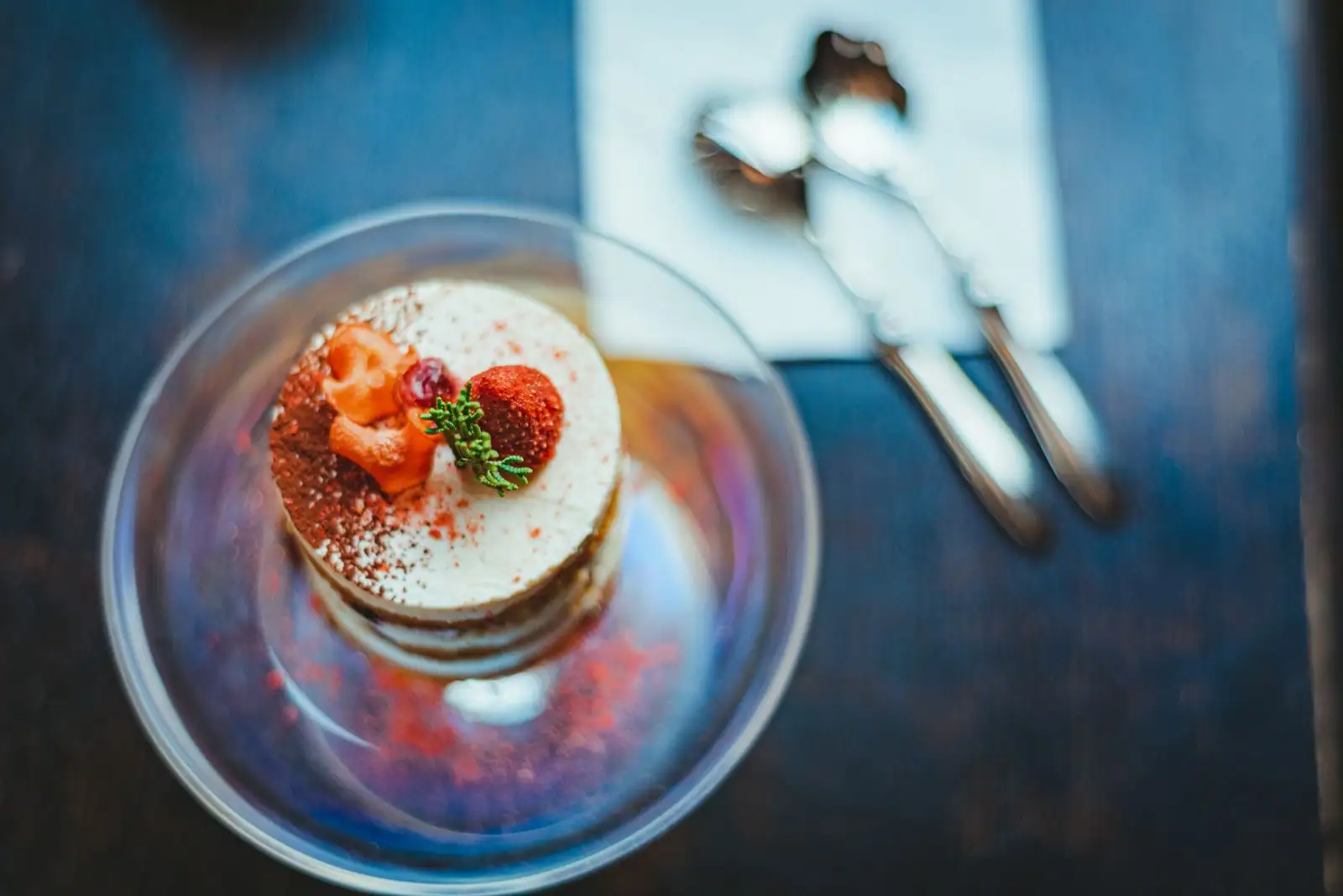 Dessert monté en verre large, crème claire, fraise et poudre rouge, photographié de dessus
