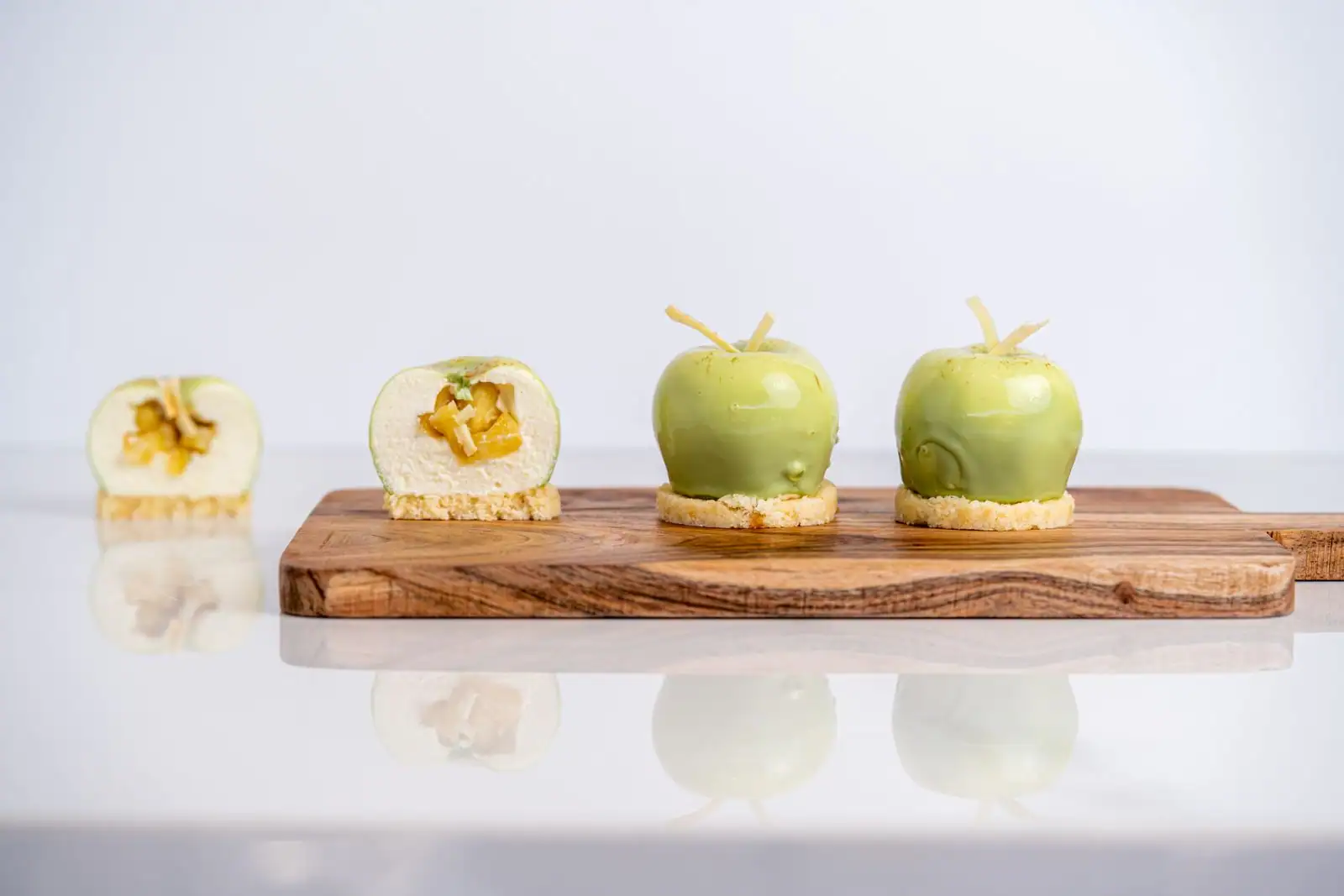 Entremets en forme de pommes vertes, deux entiers et deux coupés révélant leur mousse et leur insert